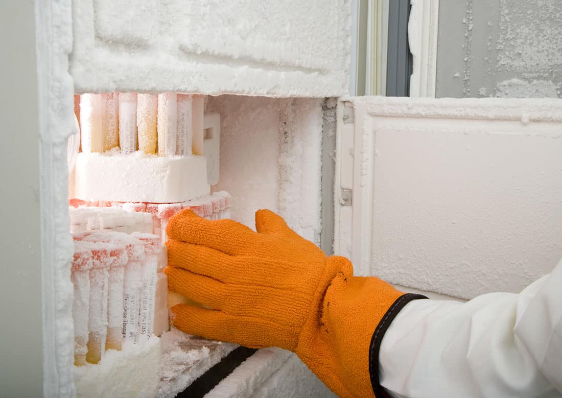 Cropped image of a researcher's arm retrieving medical samples from a freezer. Horizontal shot.